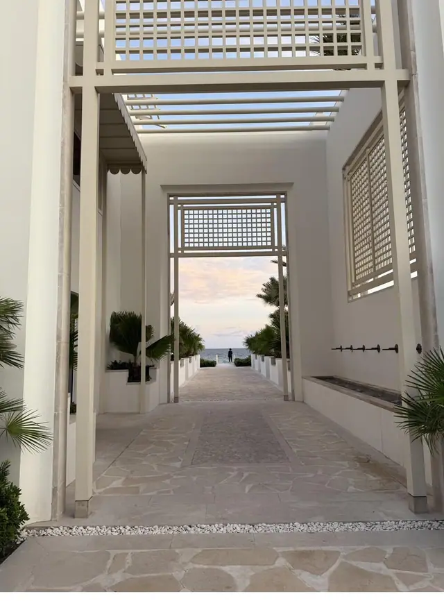 A white-walled walkway under a slatted pergola in Alys Beach, opening onto the Gulf.