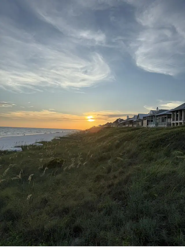 Sunset over the Gulf behind a row of beachfront houses in Rosemary Beach, seen across a sea-oat dune.
